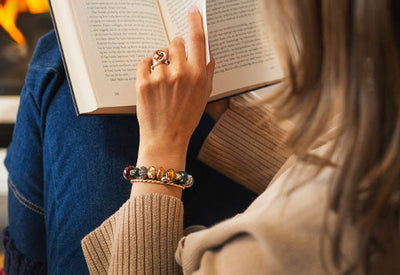 Trollbeads model reading a book by the fire, wearing the Autumn 2025 collection